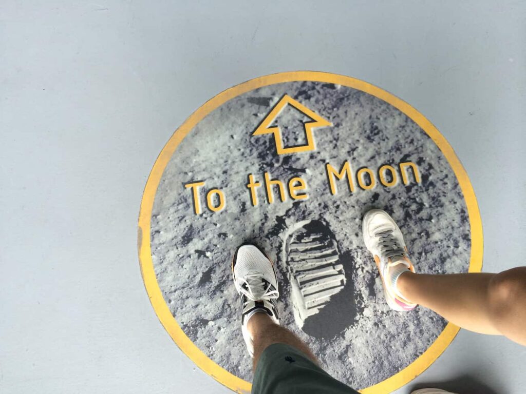 Pés aos lado de pegada na lua que indica o caminho para chegar na Lua no Kennedy Space Center, o Centro de Visitantes de NASA em Cabo Canaveral
