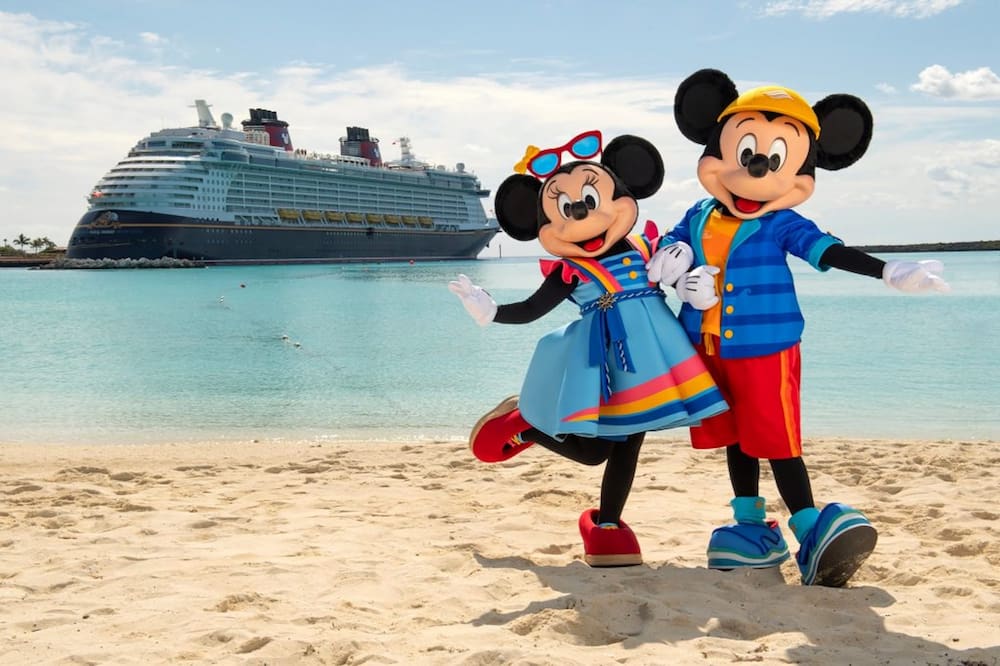 Mickey e Minnie na praia da ilha privativa da Disney em frente ao navio da Disney Cruise Line