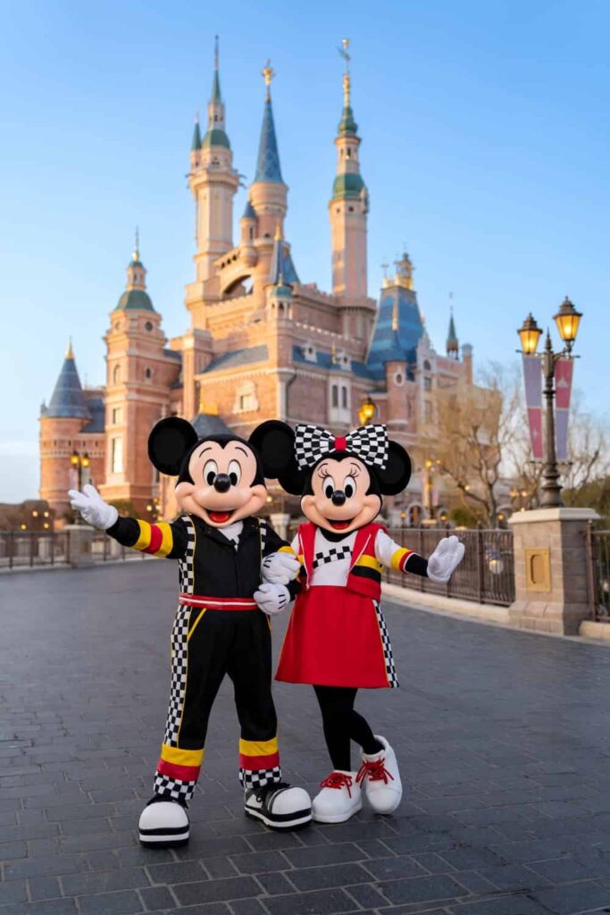 Minnie e Mickey em frente ao castelo da Disneyland Shangai com suas roupas de corredores de Fórmula 1