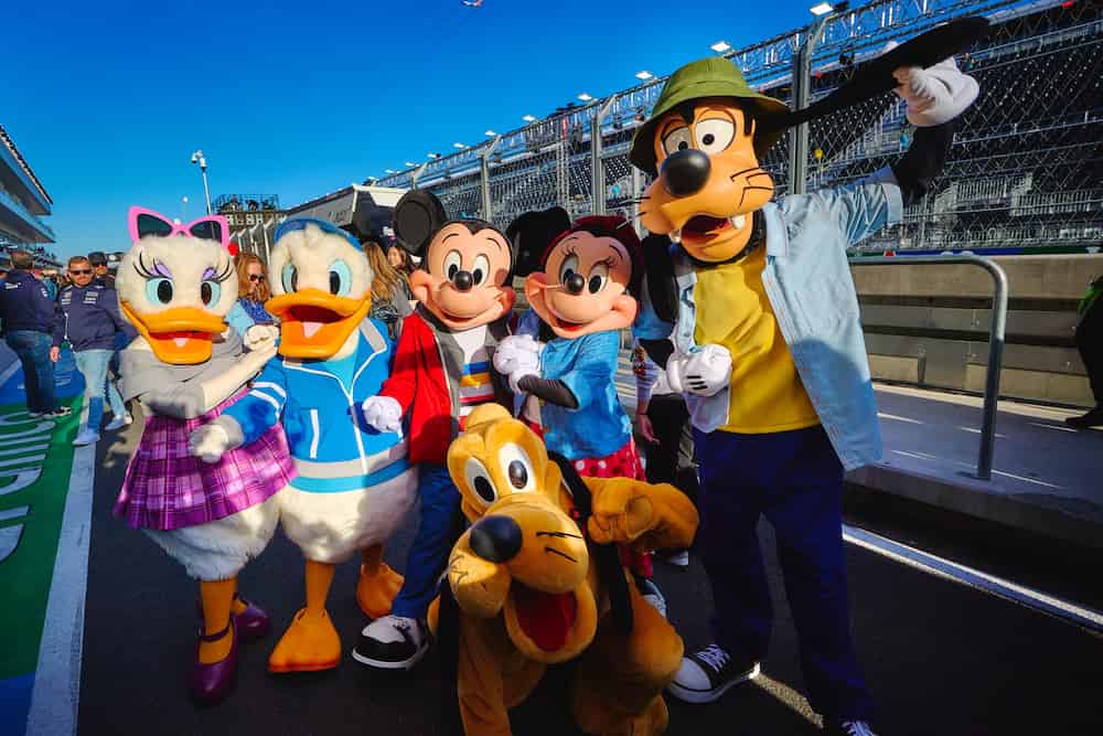 Margarida, Donald, Mickey, Minnie, Pluto e Pateta posam com roupas descoladas e fashion em pista de corrida de fórmula 1