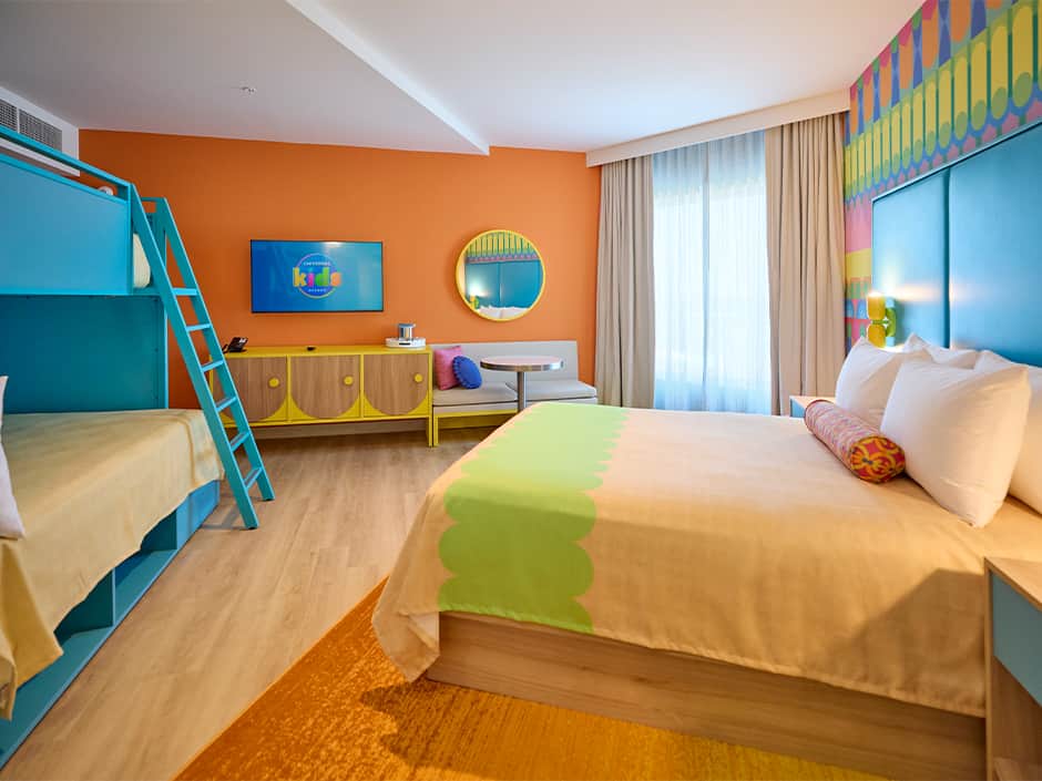 Quarto do hotel Universal Kids Resort em Frisco no Texas, com paredes coloridas em contraste com os móveis também alegres, é possível ver uma disposição diferente nos móveis, uma beliche e uma cama queen