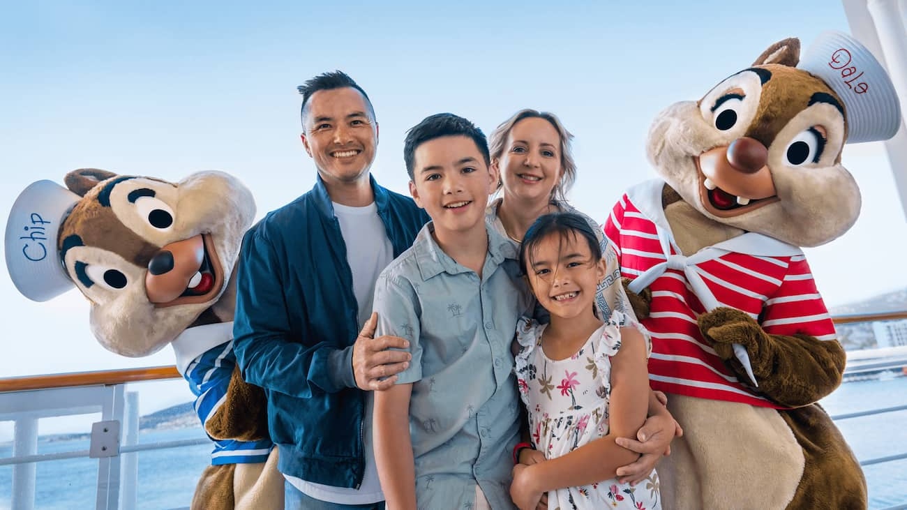 Família com pai, mãe, filha e filho posam com Tico e Teco em navio do Disney Cruise Line