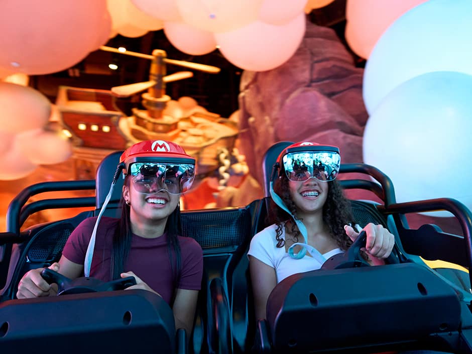 Amigas se divertem ao pilotar kart durante a atração Mario Kart Bowser's Challenge no Epic Universe da Universal Studios Florida em Orlando