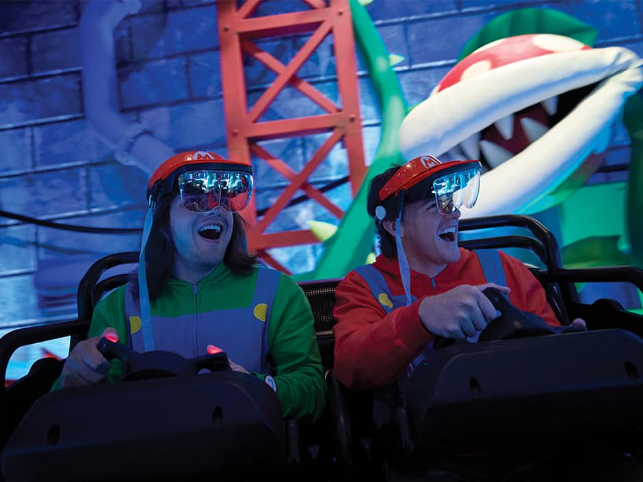Amigos com roupa de Mario e Luigi se divertem ao pilotar kart durante a atração Mario Kart Bowser's Challenge no Epic Universe da Universal Studios Florida em Orlando