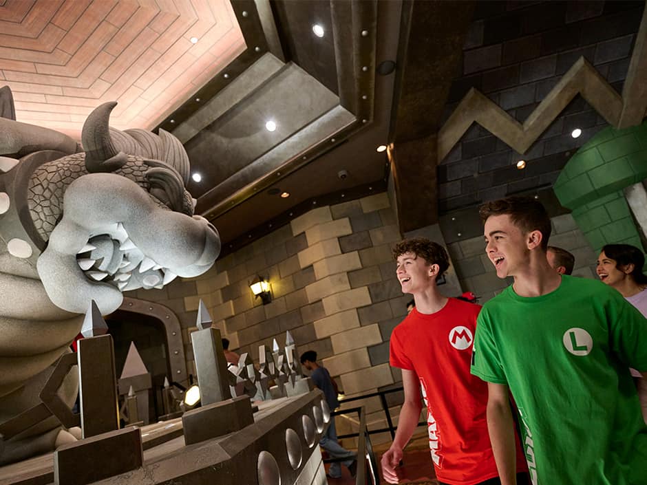 Visitantes admiram a estátua do Bowser na fila do Mario Kart Bowser's Challenge no Epic Universe em Orlando