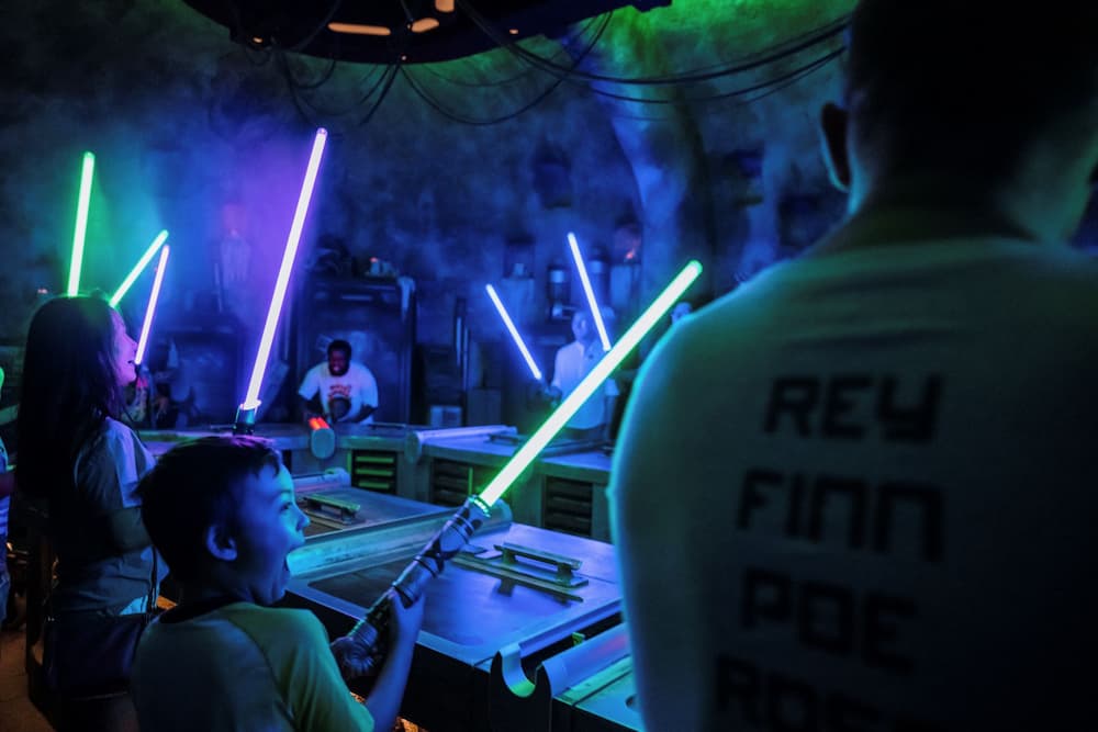 Pessoas com seus sabres de luz prontos em Galaxy's Edge na experiência Savi's Workshop onde os visitantes constroem seus sabres de luz no Hollywood Studios, parque temático da Disney