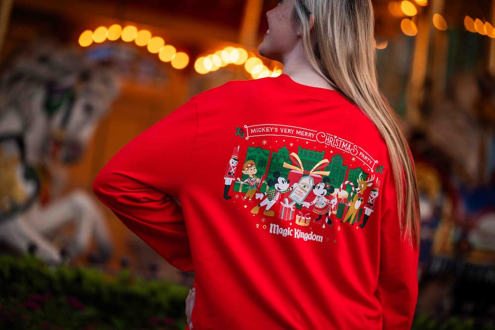 Mulher usando camiseta de merchandising especial da festa de natal do Magic Kingdom Mickey's Very Merry Christmas Party 2026