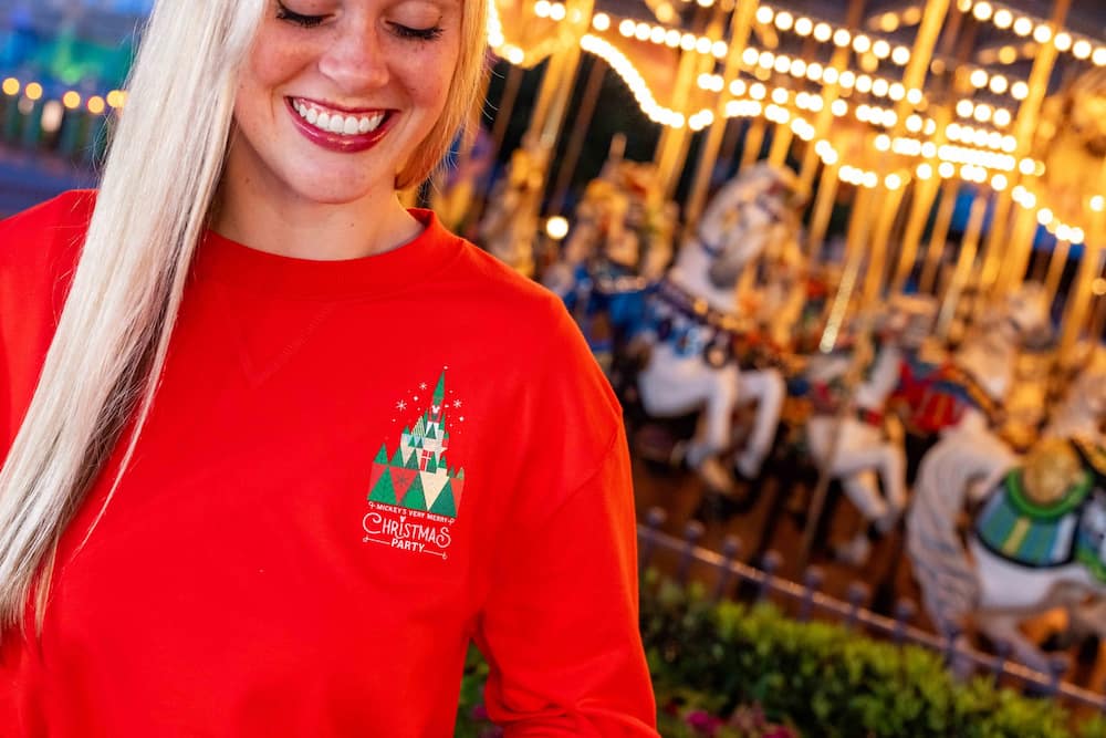 Mulher usando camiseta de merchandising especial da festa de natal do Magic Kingdom Mickey's Very Merry Christmas Party 2026