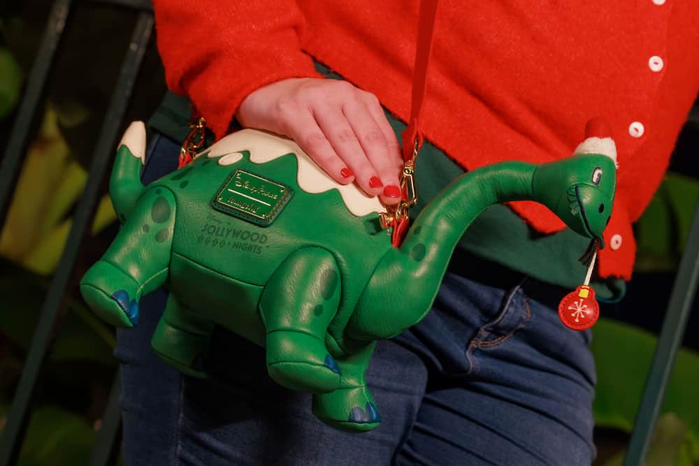 Mulher usando bolsa loungfly de merchandising especial da festa de natal do Hollywood Studios, a Jollywood Nights 2026